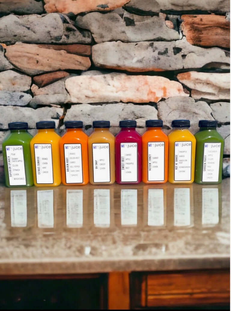 Assorted organic cold-pressed juices lined up on a countertop, showcasing fresh local produce.